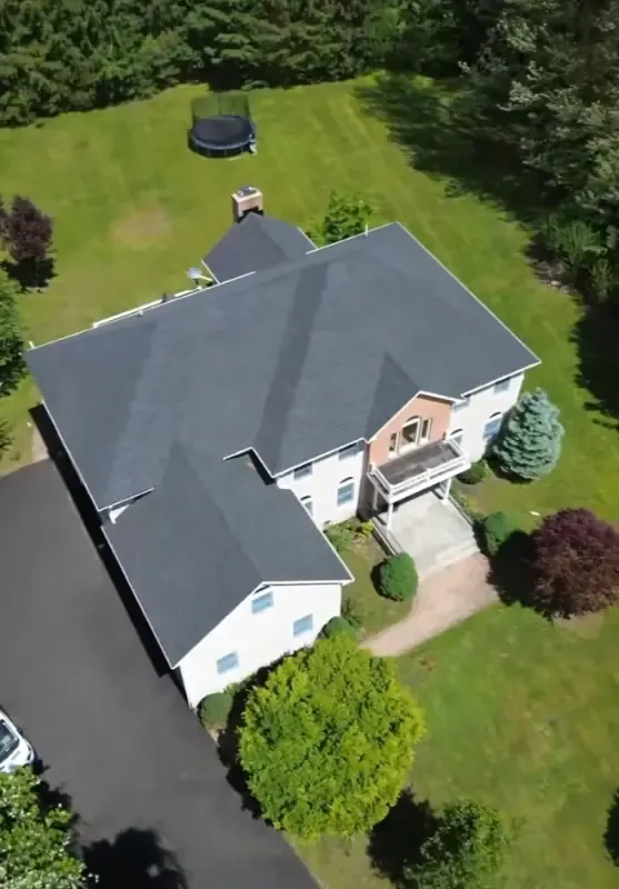 Aerial view of a white two-story home with a new roof and front porch