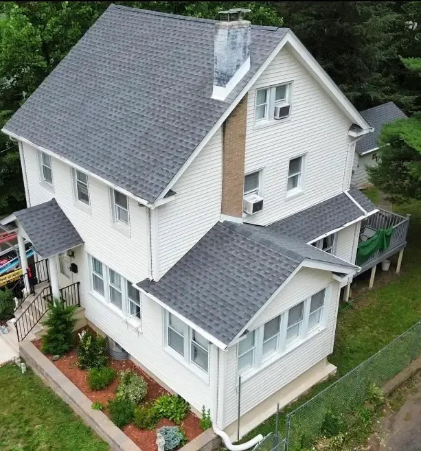 Aerial view of a white colonial home with a new dark shingle roof
