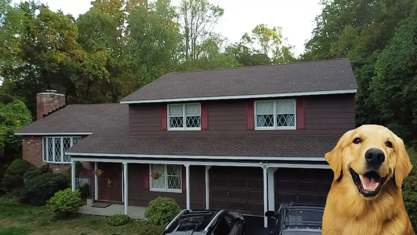 Brown wood-sided home with a new dark asphalt shingle roof and brick chimney